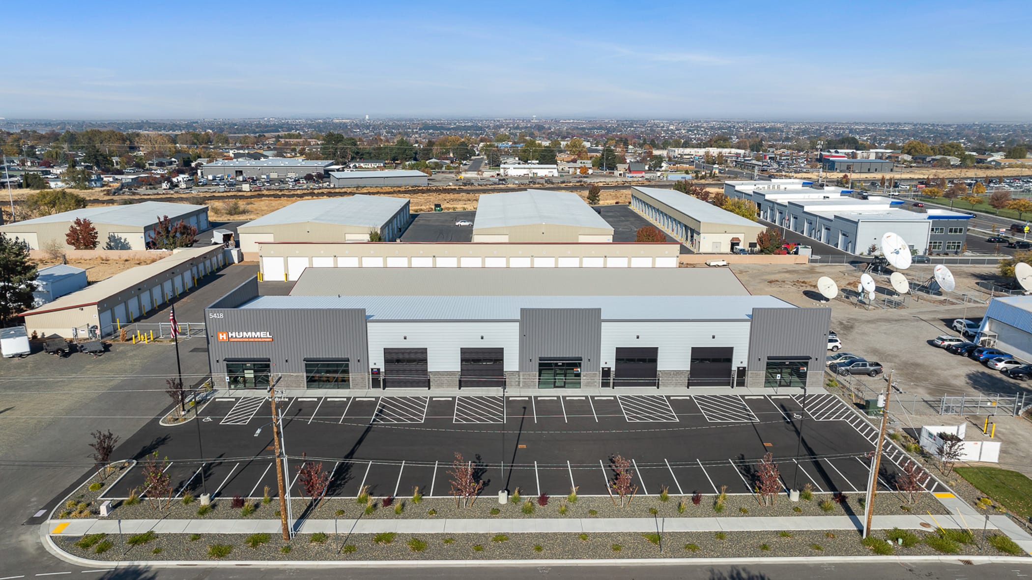 Industrial buildings with parking and satellite dishes.