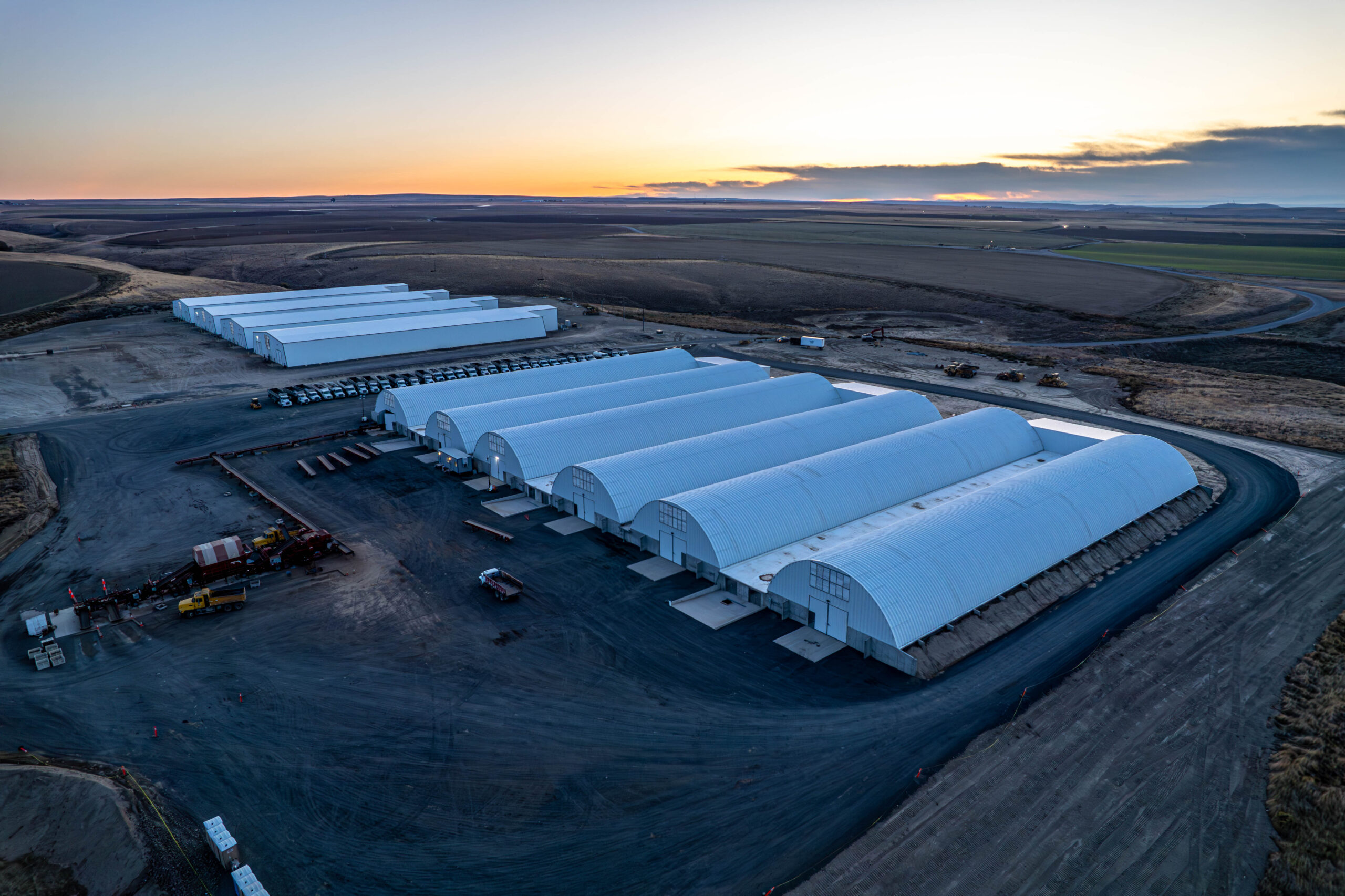 Aerial view of large industrial warehouses at sunset.