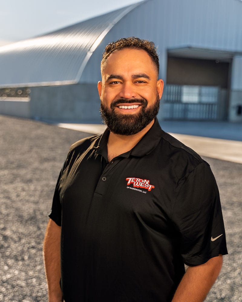 Man smiling in front of industrial building