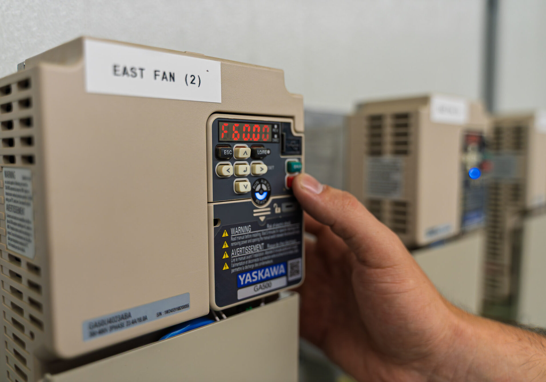 Hand adjusting industrial fan control panel.